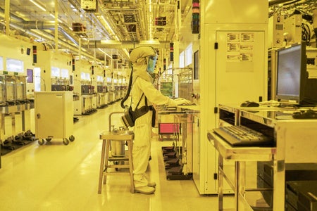 A lab technician seen under intense yellow lighting conditions of a high tech lab facility.