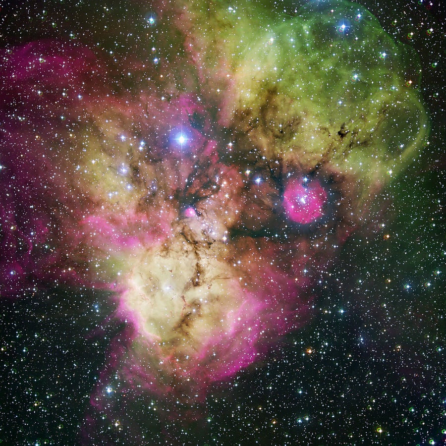 Area surrounding the stellar cluster NGC 2467, located in the southern constellation of Puppis ("The Stern"). The image, looking like a colourful cosmic ghost or a gigantic celestial Mandrill, contains the open clusters Haffner 18 (centre) and Haffner 19 (middle right: it is located inside the smaller pink region — the lower eye of the Mandrill), as well as vast areas of ionised gas. The bright star at the centre of the largest pink region on the bottom of the image is HD 64315, a massive young star that is helping shaping the structure of the whole nebular region
